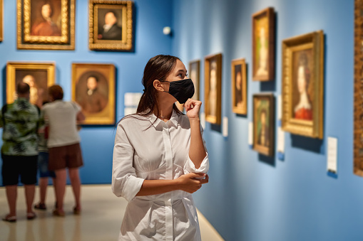 woman visitor wearing an antivirus mask in the historical museum looking at pictures