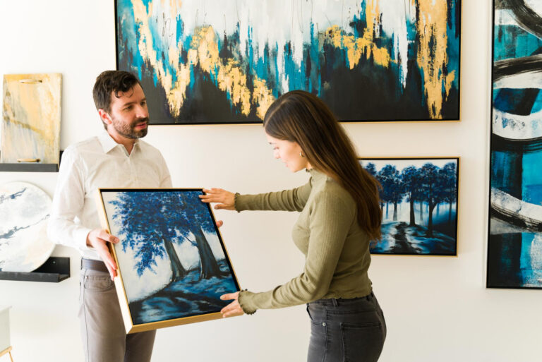 Male artist showing his painting to female client interested in buying some artwork from an exhibition of an art gallery.