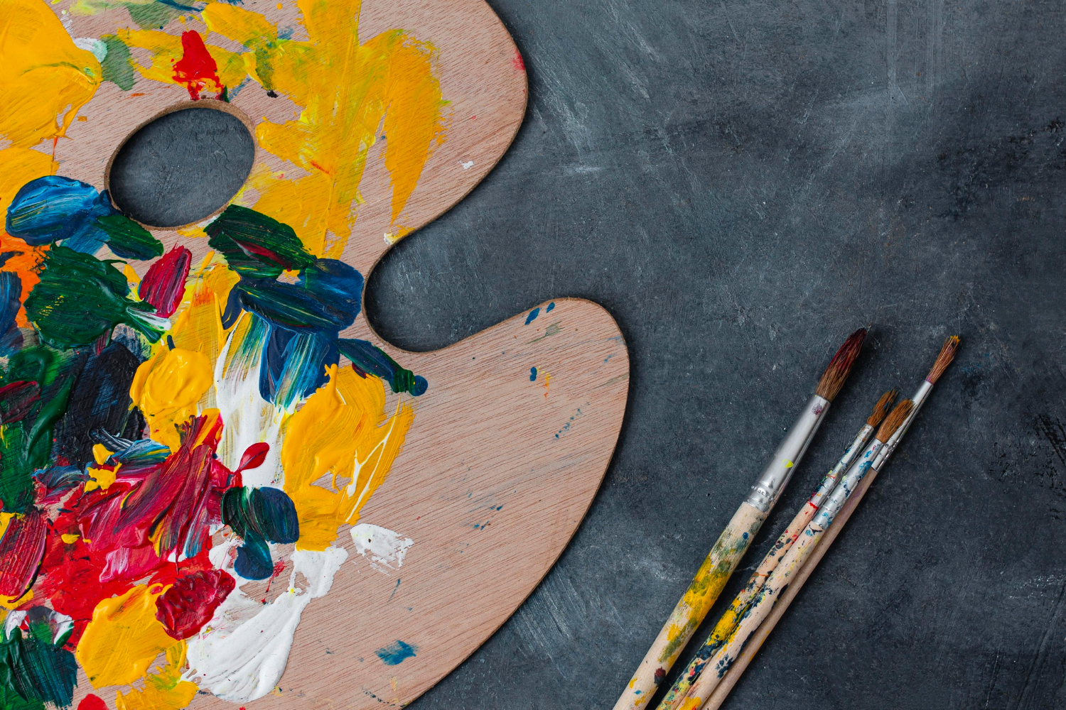 An image of an artist's easel and paintbrushes.