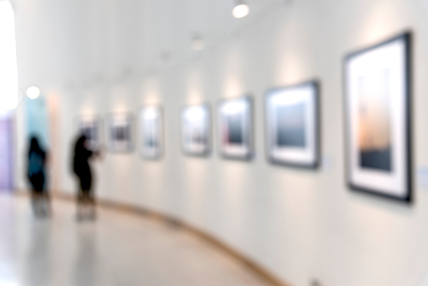 A blurry image of people enjoying an art exhibition in the background.