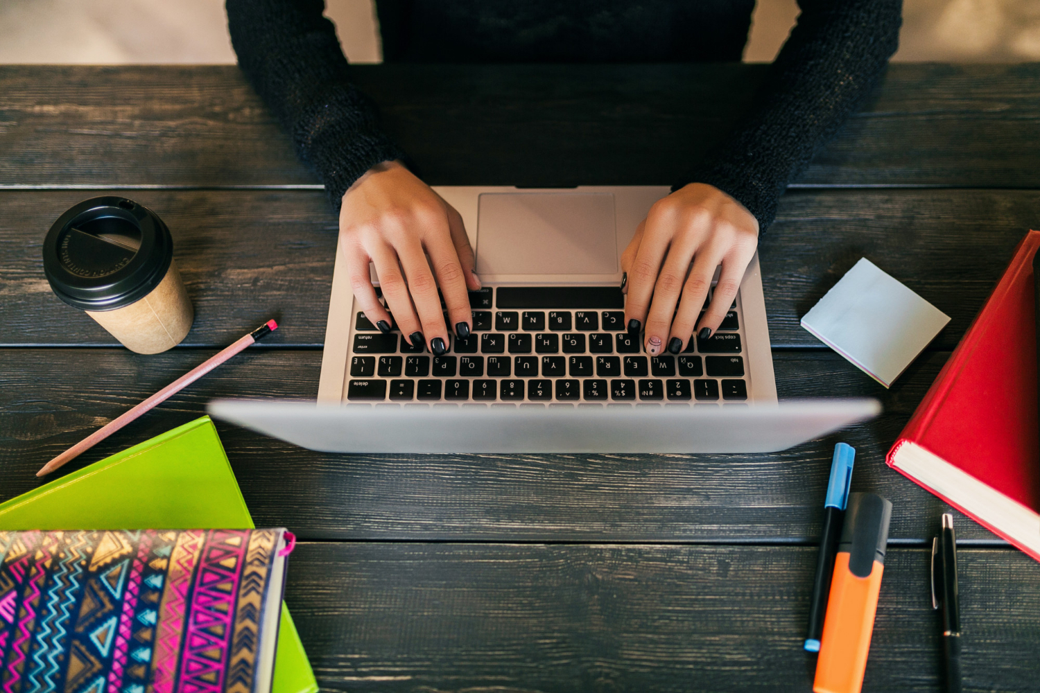 Overhead view of a woman's hands working on a laptop.